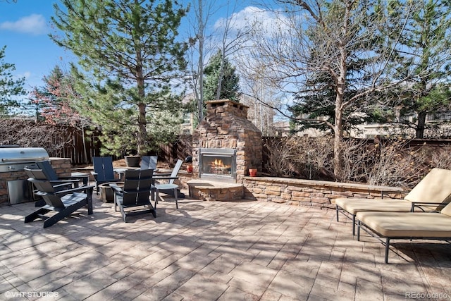 view of patio featuring a fenced backyard and an outdoor stone fireplace