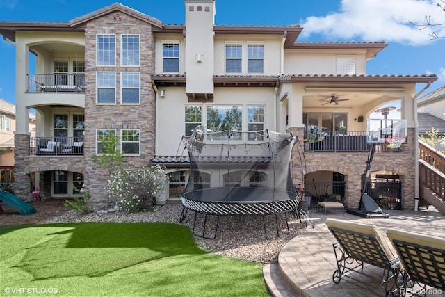 back of house featuring stucco siding, stone siding, a chimney, and a patio