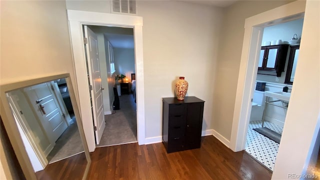 corridor featuring dark wood-type flooring, baseboards, and visible vents