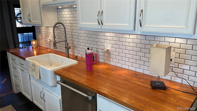 kitchen with a sink, white cabinets, tasteful backsplash, and butcher block counters