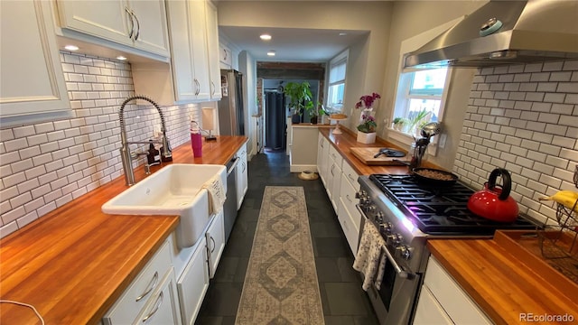 kitchen with stainless steel appliances, range hood, butcher block counters, and white cabinets