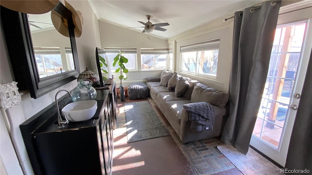 living area featuring lofted ceiling, ornamental molding, and a ceiling fan