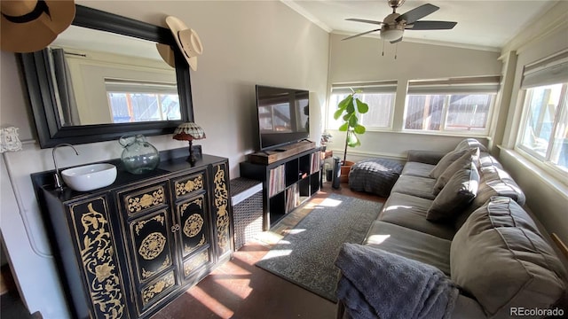 living area featuring lofted ceiling, a healthy amount of sunlight, ornamental molding, and a ceiling fan