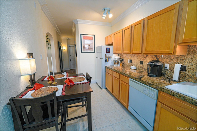 kitchen with sink, white appliances, decorative backsplash, light tile patterned floors, and ornamental molding