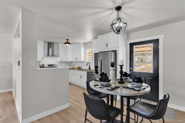 dining space with sink, a notable chandelier, and light hardwood / wood-style floors