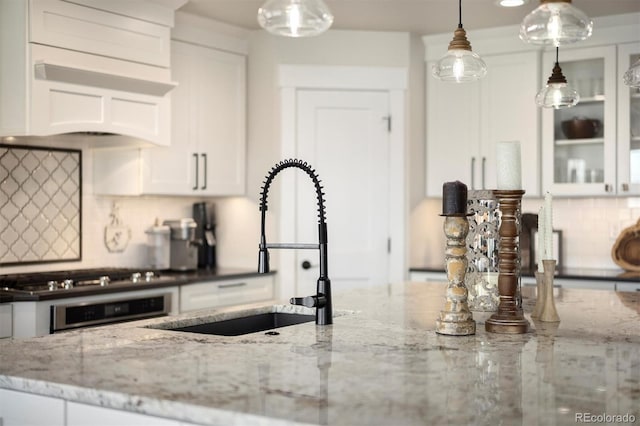 kitchen featuring a sink, custom range hood, stainless steel appliances, backsplash, and white cabinets