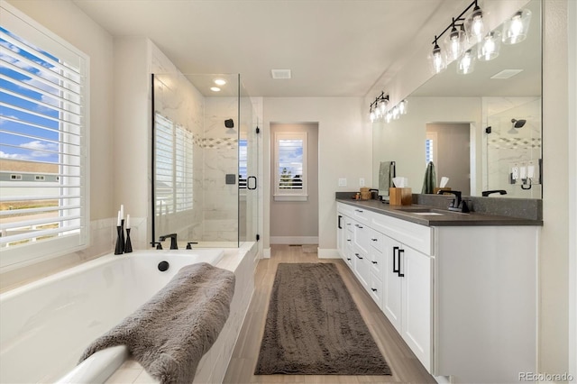 bathroom featuring a garden tub, a shower stall, plenty of natural light, double vanity, and recessed lighting