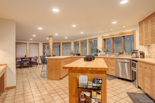 2720 S Spring Gulch Rd, Idaho Springs, CO 80452 - kitchen featuring stainless steel dishwasher, wooden counters, light brown cabinetry, a center island, and a breakfast bar area