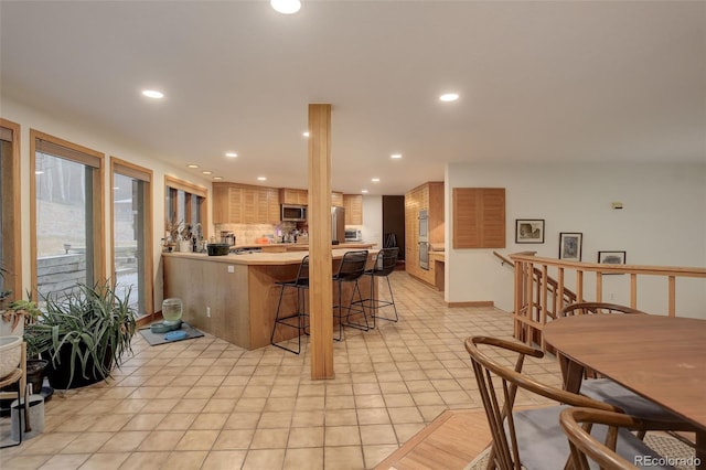 2720 S Spring Gulch Rd, Idaho Springs, CO 80452 - kitchen with stainless steel appliances, a breakfast bar area, a peninsula, recessed lighting, and light countertops
