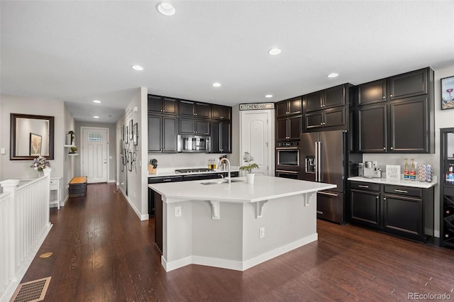 398 Midden Pl, Castle Rock, CO 80104 - kitchen featuring appliances with stainless steel finishes, light countertops, dark wood-type flooring, recessed lighting, and a kitchen island with sink