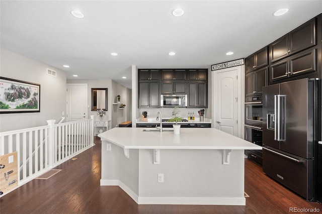 398 Midden Pl, Castle Rock, CO 80104 - kitchen featuring appliances with stainless steel finishes, light countertops, an island with sink, dark wood-style flooring, and recessed lighting