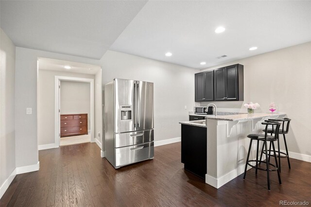 398 Midden Pl, Castle Rock, CO 80104 - kitchen featuring appliances with stainless steel finishes, a breakfast bar area, light stone counters, a peninsula, and dark wood-style flooring