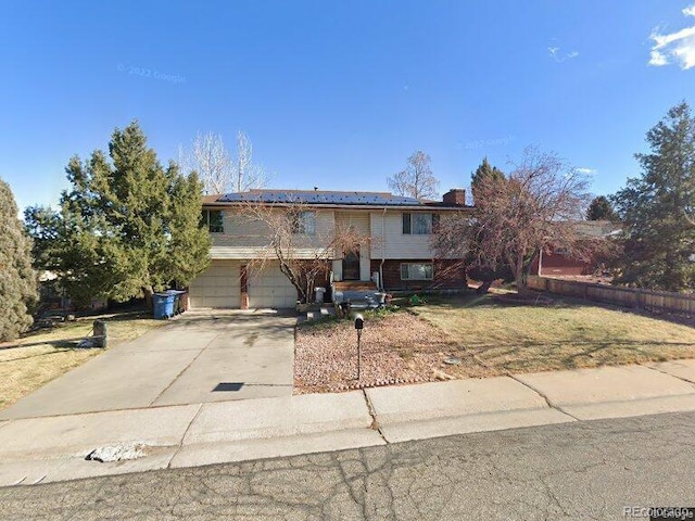 raised ranch featuring a front lawn and a garage