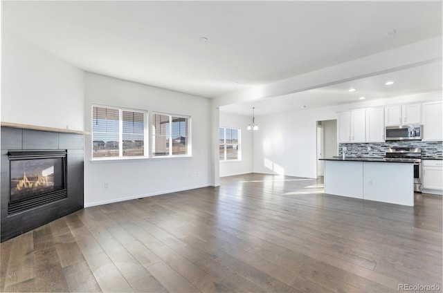 unfurnished living room with a tile fireplace, dark hardwood / wood-style floors, and an inviting chandelier