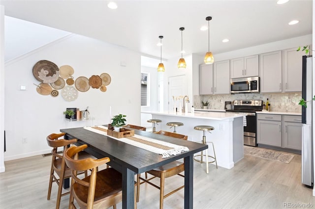8057 Monte Vista Cir, Littleton, CO 80125 - kitchen featuring appliances with stainless steel finishes, gray cabinets, light wood-style floors, decorative backsplash, and recessed lighting