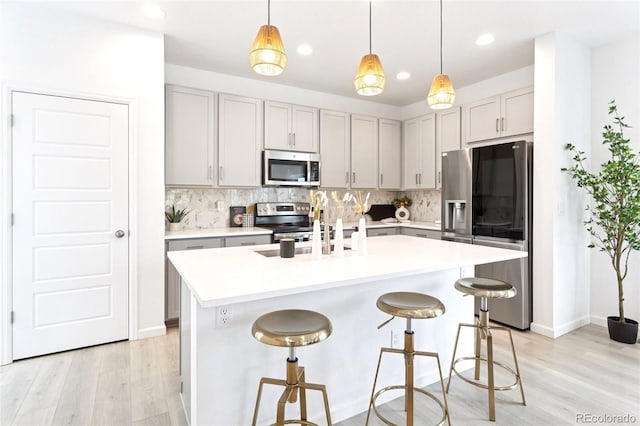 8057 Monte Vista Cir, Littleton, CO 80125 - kitchen with stainless steel appliances, gray cabinets, tasteful backsplash, light wood-style flooring, and recessed lighting