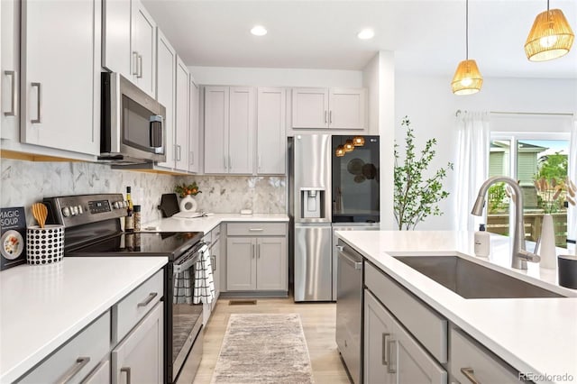 8057 Monte Vista Cir, Littleton, CO 80125 - kitchen with stainless steel appliances, a sink, gray cabinetry, light wood-style floors, and light countertops
