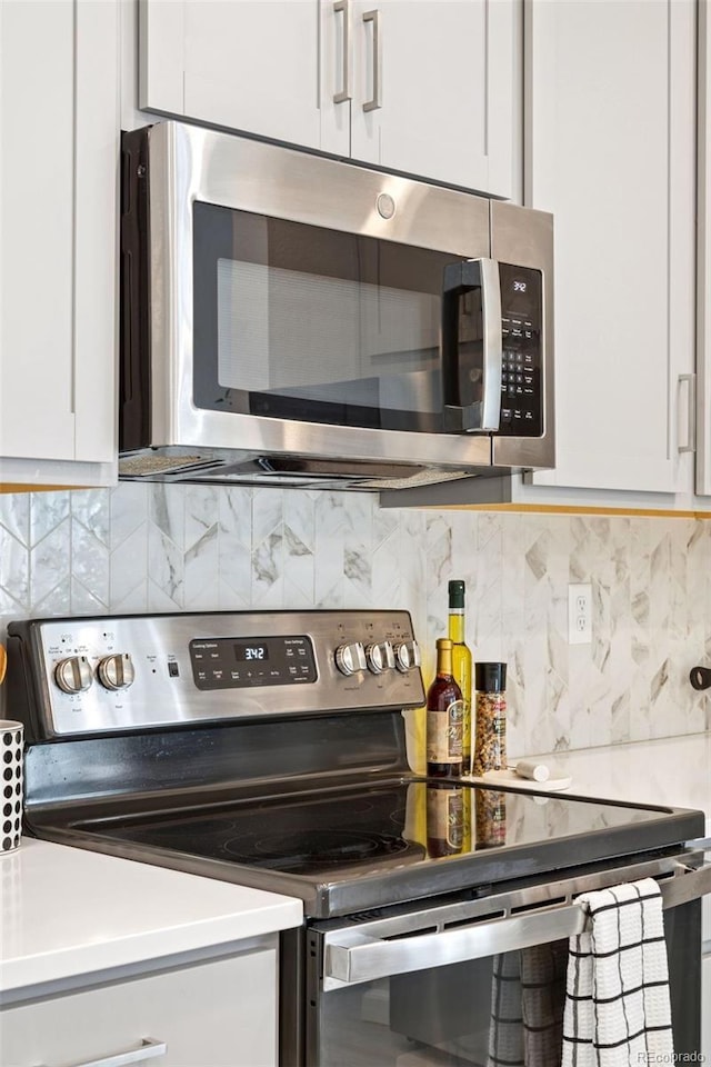 8057 Monte Vista Cir, Littleton, CO 80125 - kitchen with appliances with stainless steel finishes, decorative backsplash, white cabinetry, and light countertops