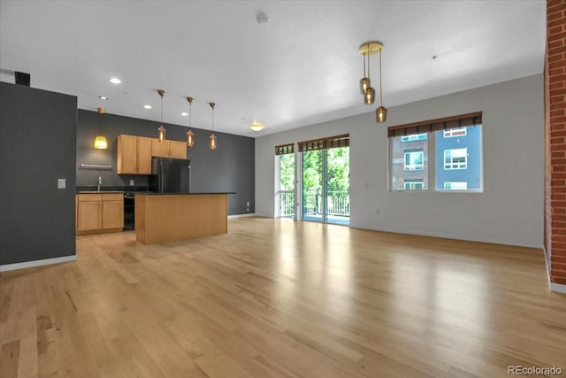 1438 Little Raven St Unit 201, Denver, CO 80202 - kitchen featuring freestanding refrigerator, dark countertops, light brown cabinetry, light wood-type flooring, and open floor plan