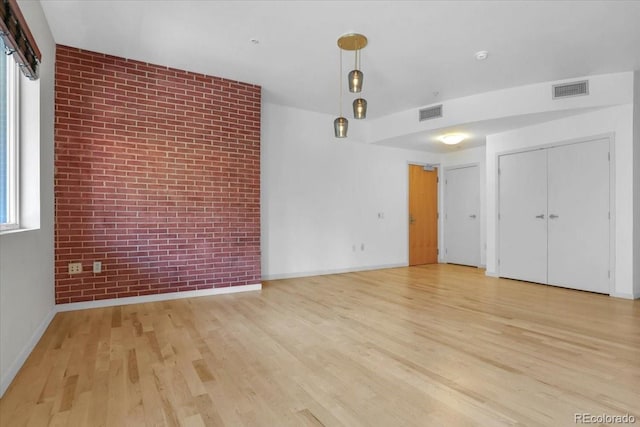1438 Little Raven St Unit 201, Denver, CO 80202 - unfurnished living room featuring brick wall and light wood-style flooring