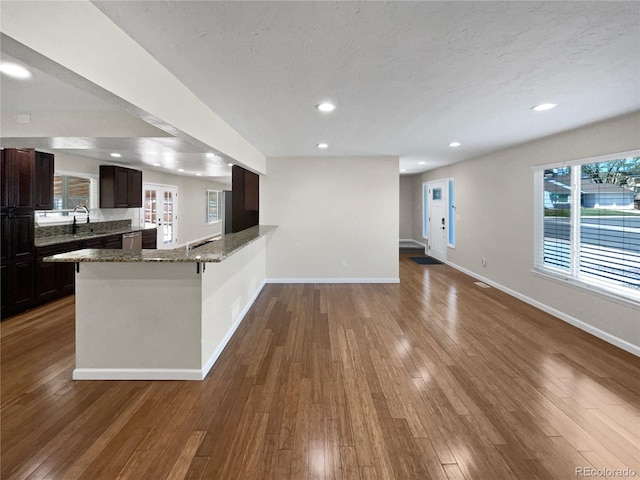 5480 W 74th Ave, Arvada, CO 80003 - kitchen with baseboards, dark brown cabinetry, a peninsula, light stone countertops, and open floor plan