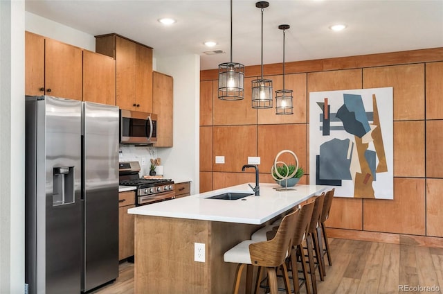 kitchen featuring sink, light hardwood / wood-style flooring, a breakfast bar area, a center island with sink, and appliances with stainless steel finishes