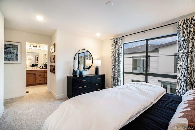 bedroom featuring ensuite bathroom and light colored carpet