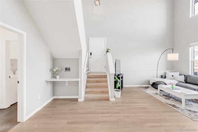 interior space with light wood-type flooring and a towering ceiling