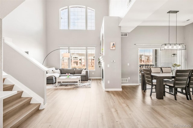 foyer with light hardwood / wood-style floors, a notable chandelier, and a towering ceiling