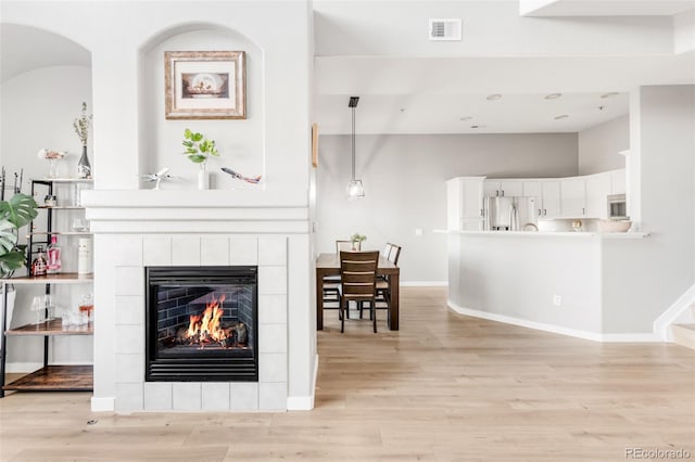 living room featuring a tiled fireplace and light wood-type flooring