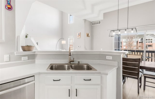 kitchen featuring pendant lighting, dishwasher, sink, white cabinetry, and light tile patterned floors