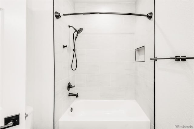 bathroom with toilet and tiled shower / bath