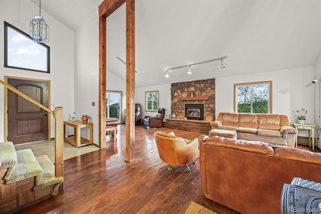 2169 Vigilante Ave, Bailey, CO 80421 - living area with a stone fireplace, vaulted ceiling, plenty of natural light, hardwood / wood-style floors, and track lighting