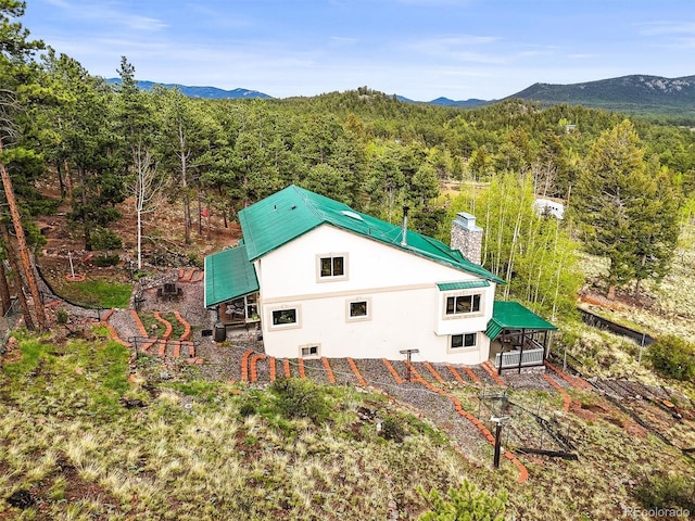 2169 Vigilante Ave, Bailey, CO 80421 - view of side of home with a chimney, a mountain view, stucco siding, and a forest view