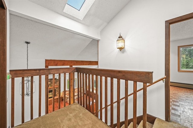 2169 Vigilante Ave, Bailey, CO 80421 - hallway featuring a textured ceiling, a skylight, vaulted ceiling, a baseboard radiator, and an upstairs landing