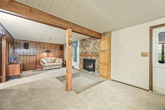 2169 Vigilante Ave, Bailey, CO 80421 - carpeted living room with wood walls, a stone fireplace, and beam ceiling