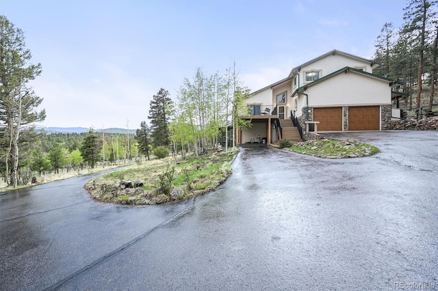 2169 Vigilante Ave, Bailey, CO 80421 - view of front of property featuring asphalt driveway, stairs, stucco siding, an attached garage, and stone siding