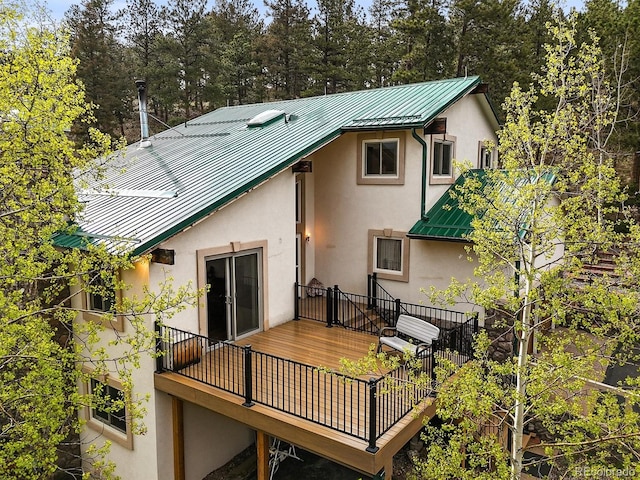 2169 Vigilante Ave, Bailey, CO 80421 - back of house featuring stucco siding, a standing seam roof, a metal roof, a wooden deck, and view of wooded area