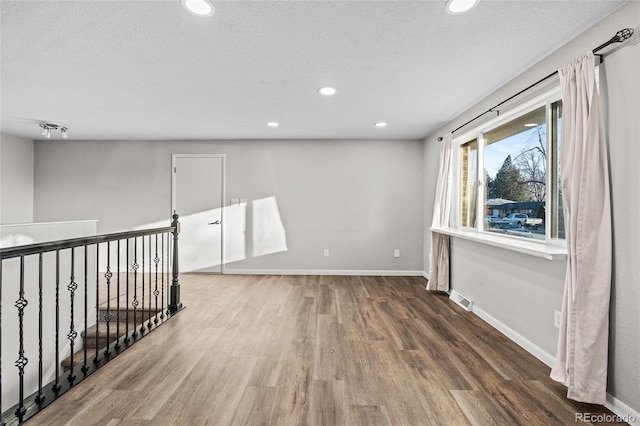 spare room featuring dark hardwood / wood-style floors and a textured ceiling