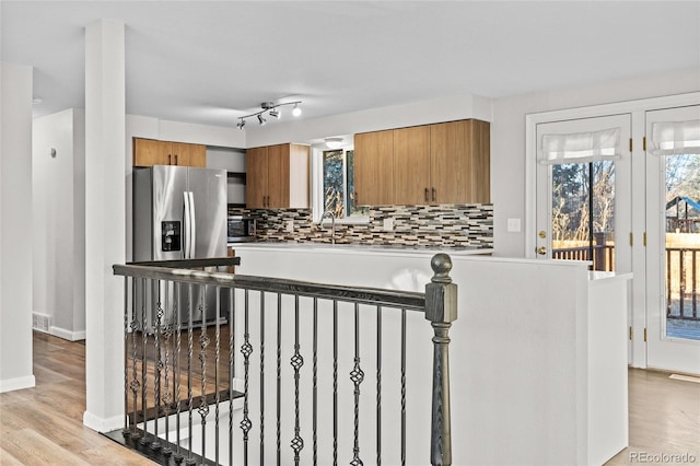 kitchen with tasteful backsplash, sink, stainless steel fridge, and light hardwood / wood-style floors