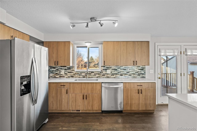 kitchen featuring dark wood-type flooring, sink, tasteful backsplash, a textured ceiling, and appliances with stainless steel finishes