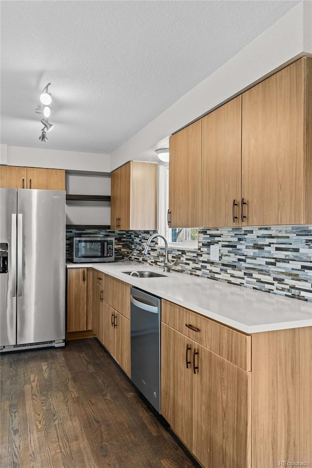 kitchen featuring sink, a textured ceiling, dark hardwood / wood-style flooring, stainless steel appliances, and backsplash