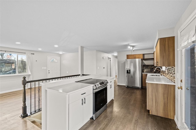 kitchen with wood-type flooring, appliances with stainless steel finishes, a kitchen island, white cabinets, and backsplash