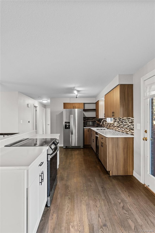 kitchen with sink, a textured ceiling, dark hardwood / wood-style floors, stainless steel appliances, and backsplash