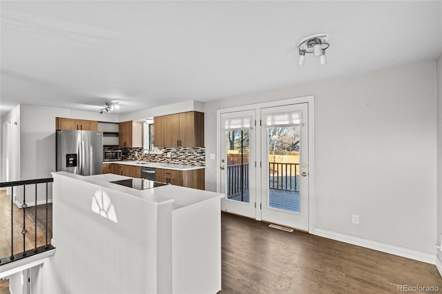 kitchen with sink, dark hardwood / wood-style floors, tasteful backsplash, black electric cooktop, and stainless steel fridge with ice dispenser