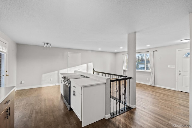 kitchen with hardwood / wood-style flooring, stainless steel electric stove, a textured ceiling, and white cabinets