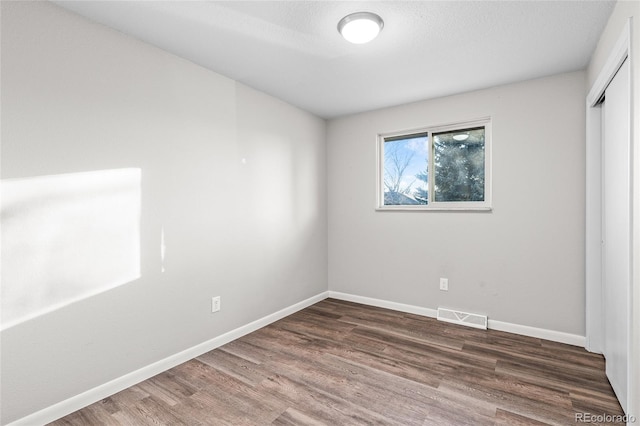 unfurnished room with dark wood-type flooring and a textured ceiling