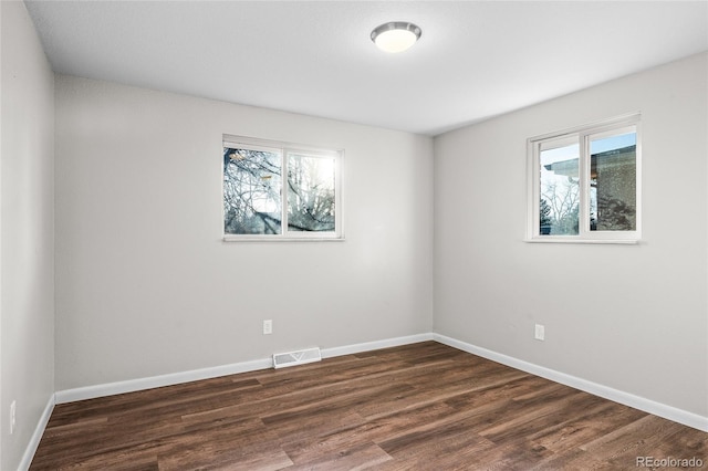 spare room with dark wood-type flooring and a wealth of natural light