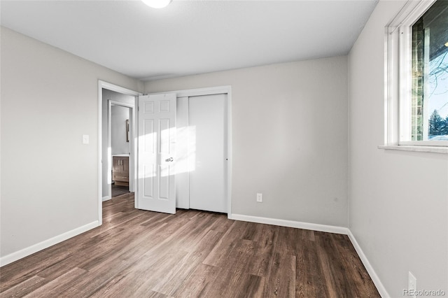 unfurnished bedroom with dark wood-type flooring and a closet