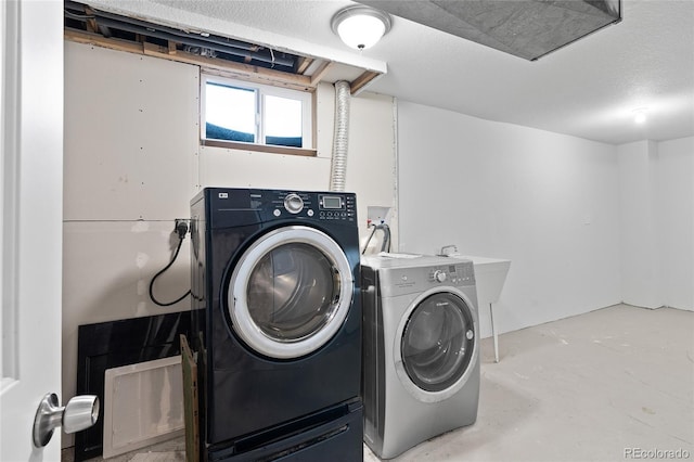 clothes washing area featuring washer and dryer and a textured ceiling